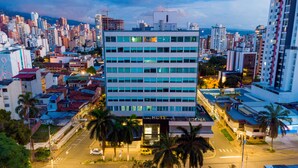 Um edifício moderno de hotel com vários andares, uma entrada destacada e uma placa visível.