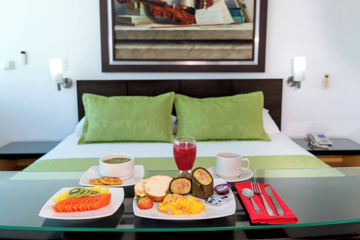 Une table de petit-déjeuner soigneusement dressée, avec des assiettes remplies de nourriture, un verre de jus de fruits et une serviette pliée avec soin.