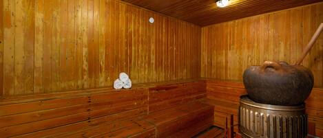 Una sauna con bancos de madera y un gran elemento calefactor de piedra.