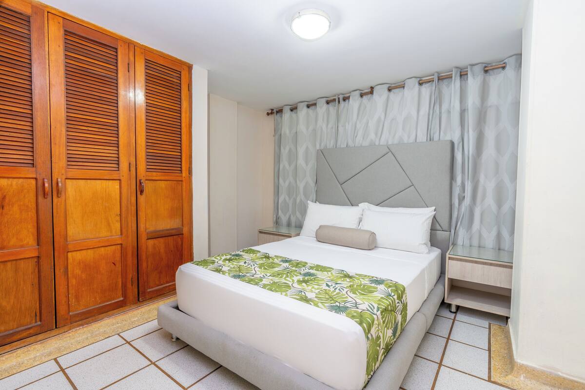 A bedroom with a bed, a wardrobe, and a nightstand.