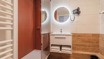 A modern bathroom with a glass shower enclosure, a white sink with a mirror above, and a towel rack.