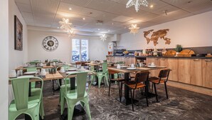 Een moderne eetruimte met groene stoelen, houten tafels en een keuken op de achtergrond.