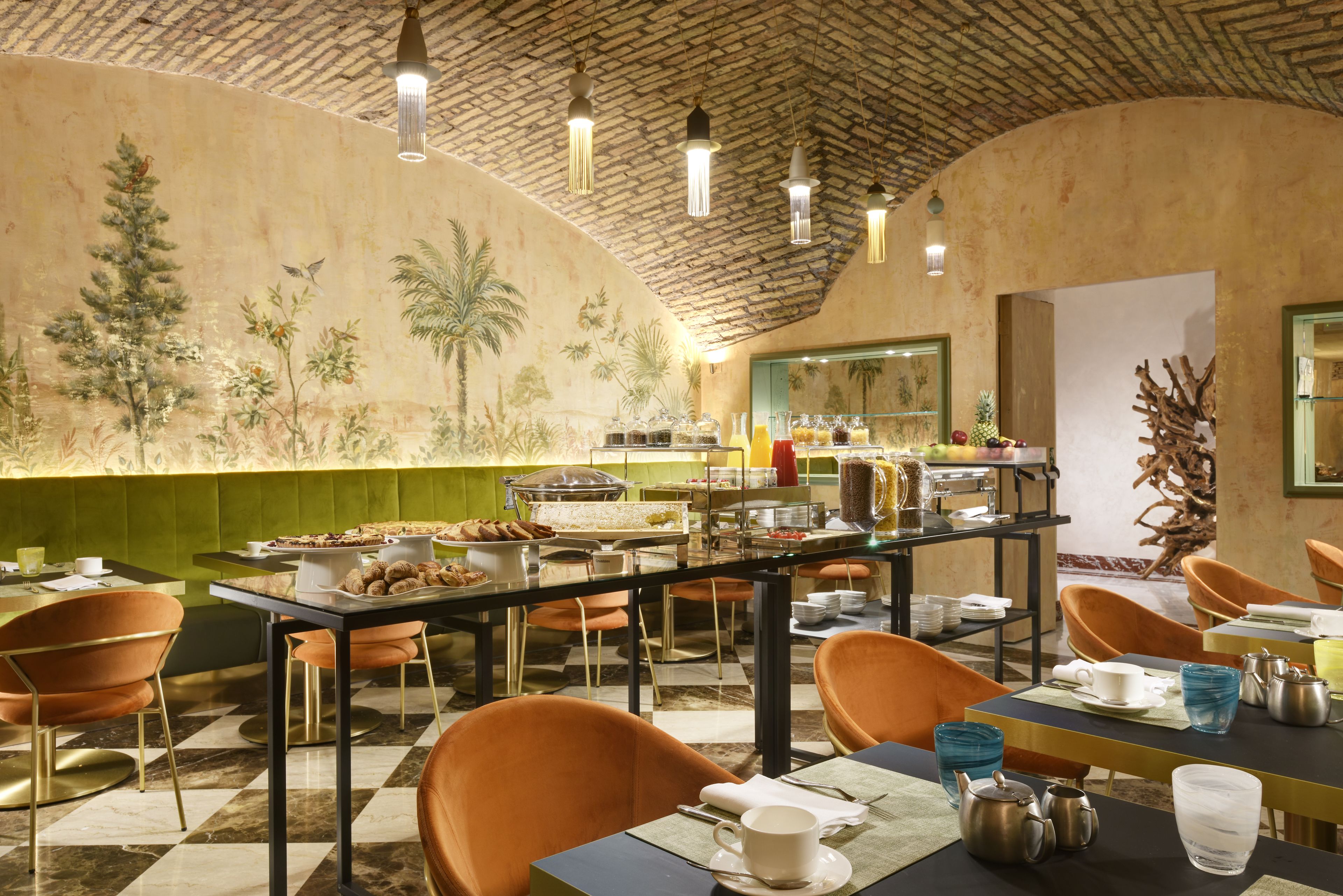 Un espace repas avec un buffet, des chaises orange et une fresque murale.