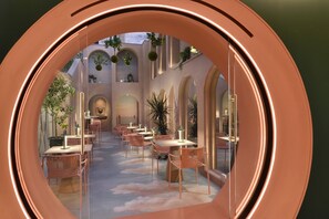 Vista circular de un comedor con mesas y sillas, techos abovedados y plantas colgantes.