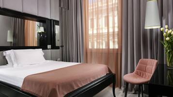 Ein Hotelzimmer mit Bett, Sessel, Lampe und einem fenster mit Vorhängen.