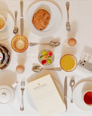 Een ontbijttafel met een croissant, fruit en drankjes.