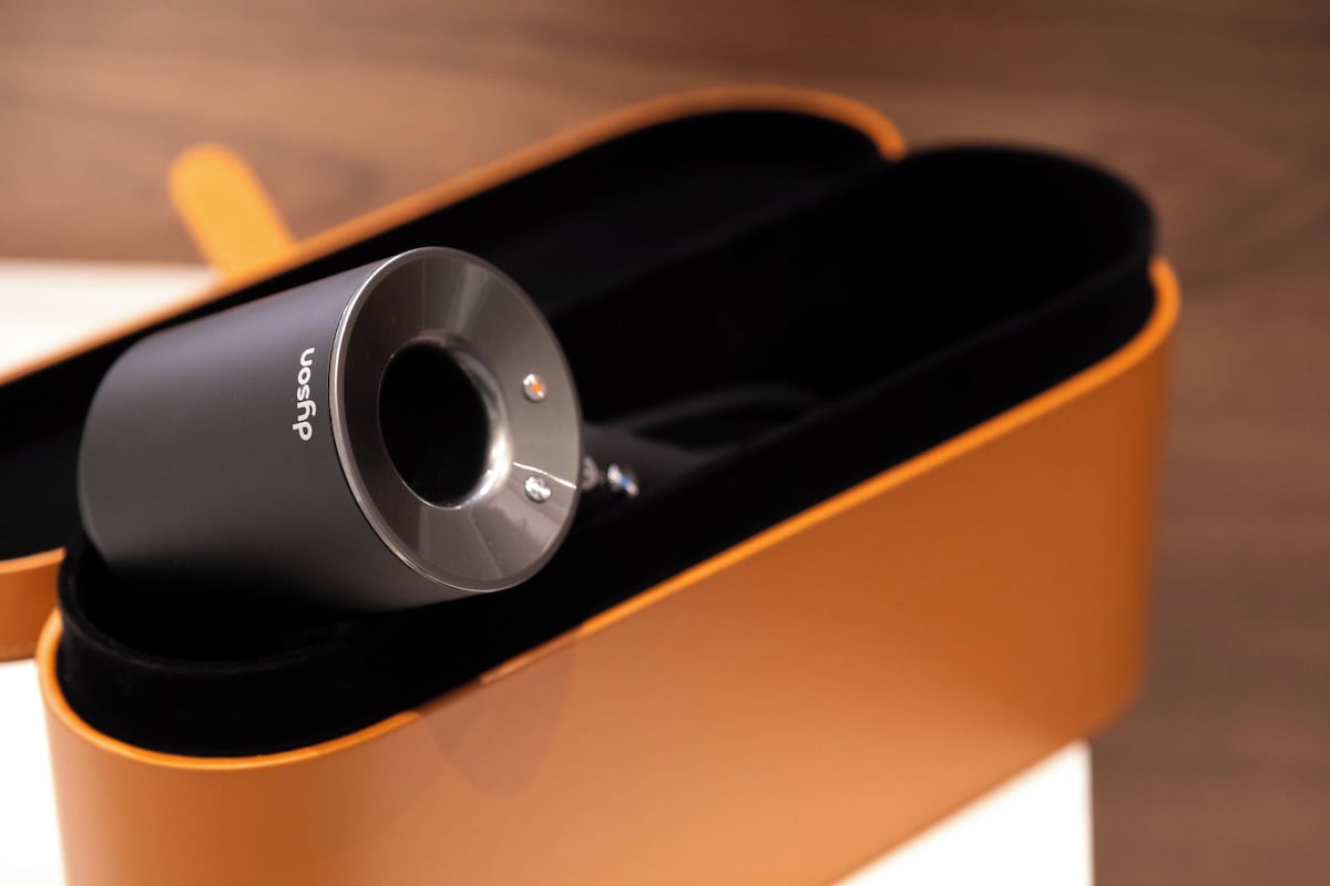 Un objet cylindrique portant une étiquette, placé à l’intérieur d’un récipient dont l’intérieur est incurvé et de couleur orange.