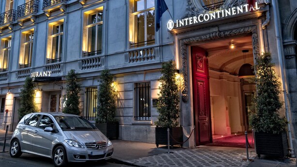 A multi-story hotel with a classic European architectural style, featuring ornate balconies and a prominent entrance with a red door.