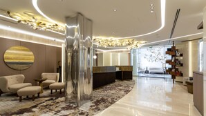 A modern lobby with a central reception desk, seating area, and a large abstract painting on the wall.