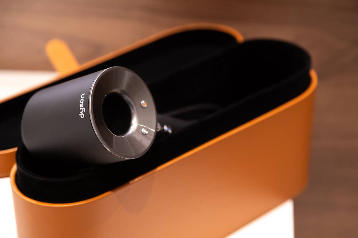 A cylindrical object with a label, placed inside a container with a curved, orange interior.