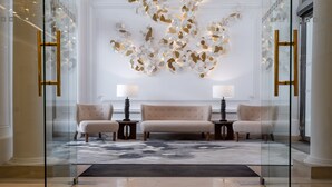 A modern lobby with a central sofa, two side chairs, and a decorative wall piece.