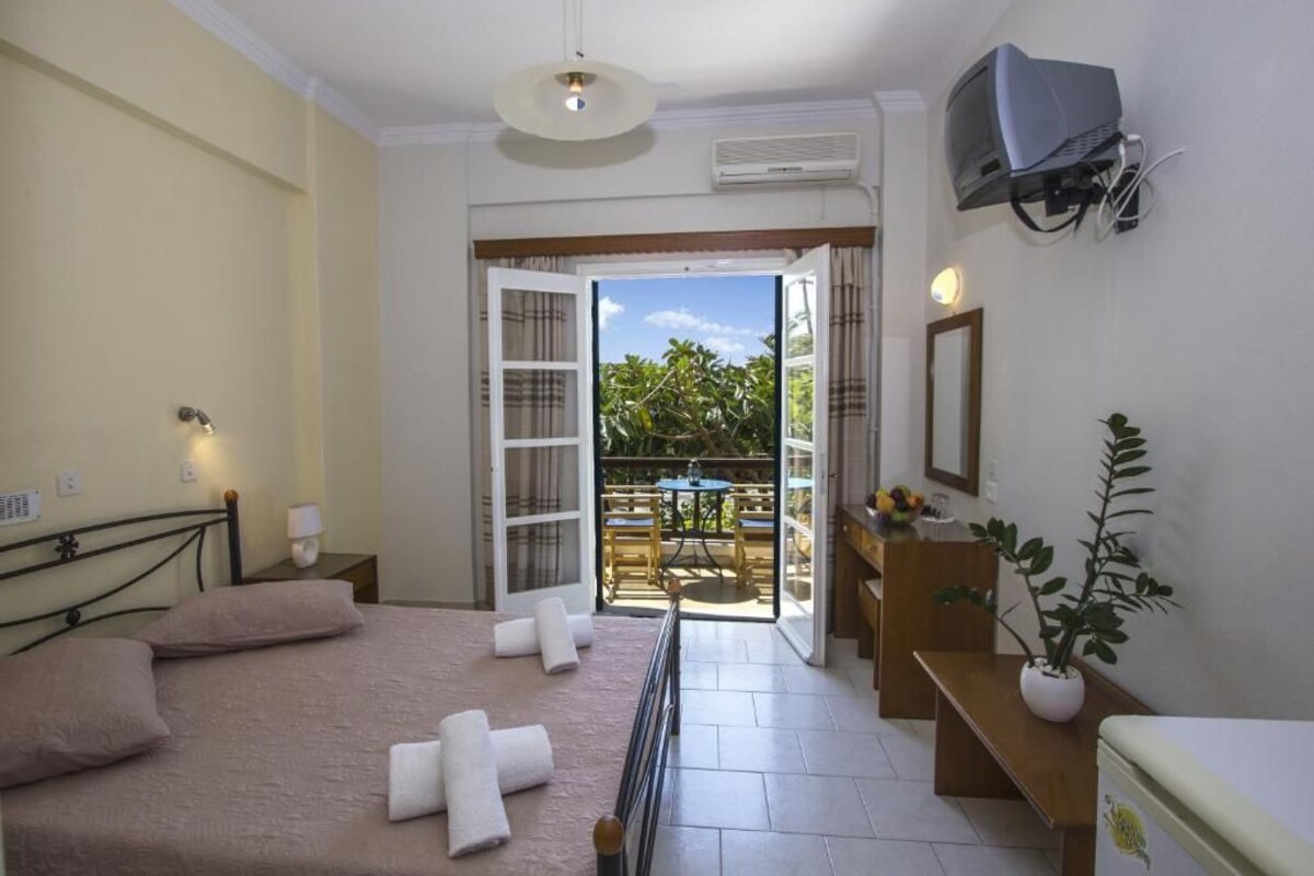 A bedroom with a bed, bedside tables, a TV, and a balcony with a view.