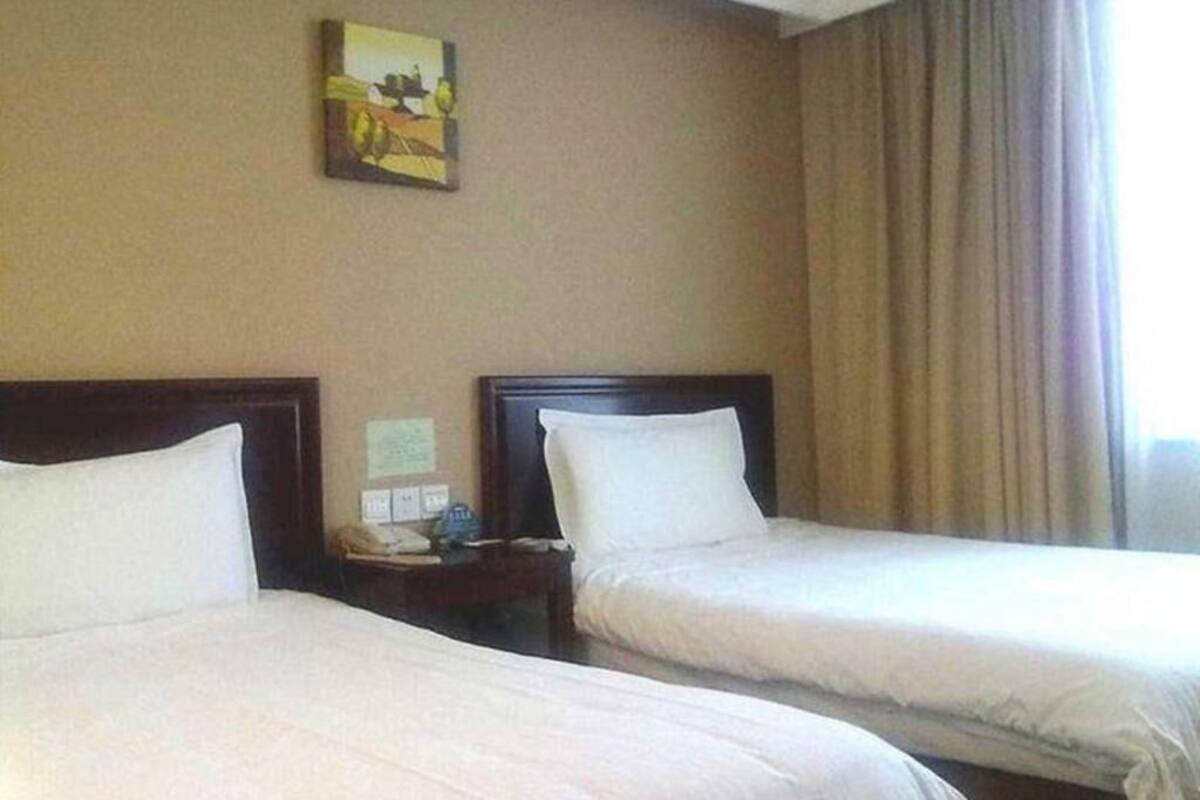 A hotel room with two beds, a nightstand with a phone, and a painting on the wall.