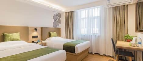 A hotel room with two beds, a desk, a chair, an air conditioning unit, and a window with curtains.