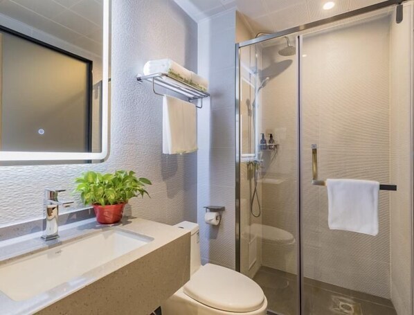 A modern bathroom with a glass shower enclosure, a sink with a potted plant, and a toilet. - Greentree Inn Beijing Fangzhuang Hotel (Beijing)