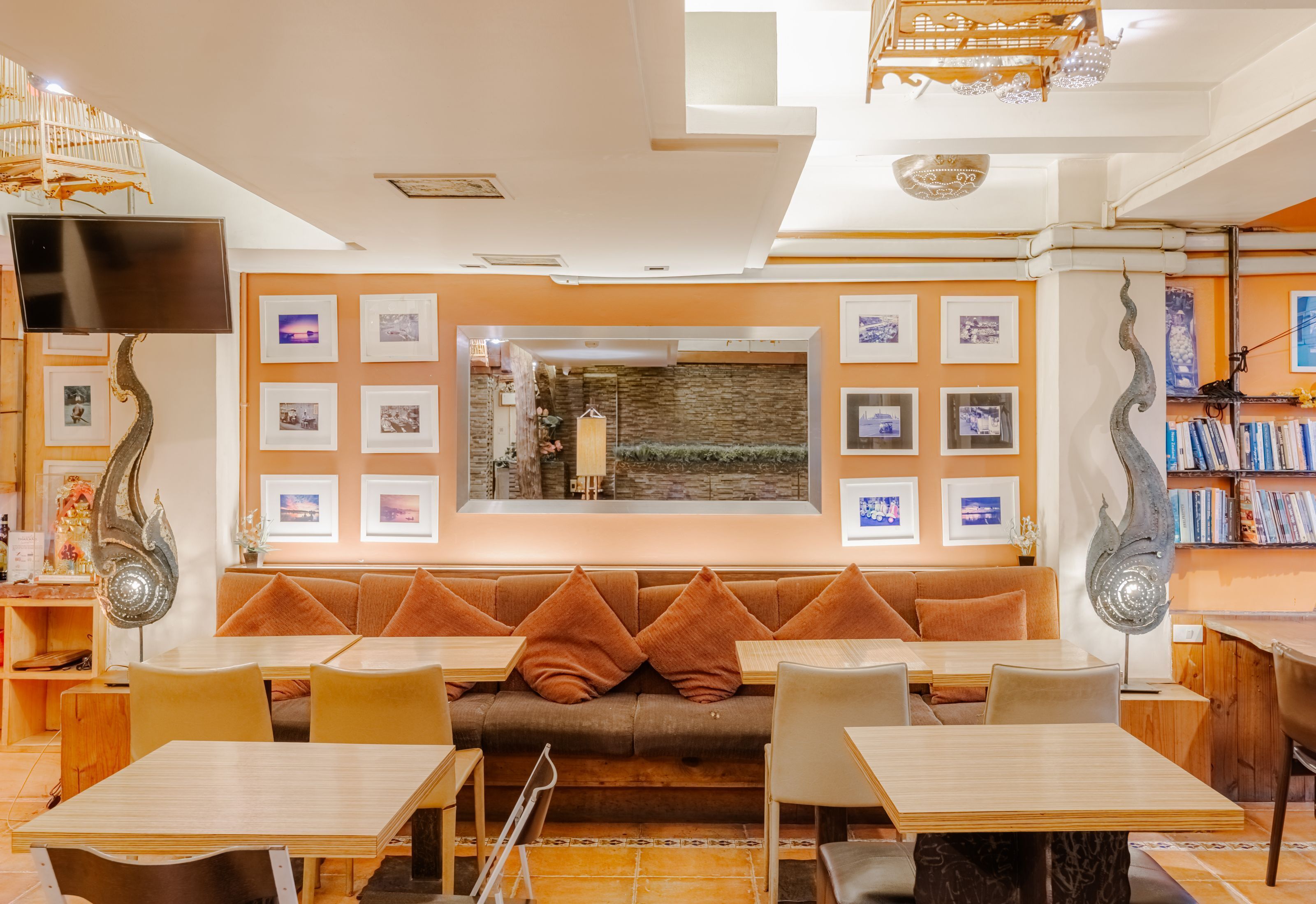A modern dining area with a central seating area, tables, and a television mounted on the wall.