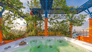 Un espace avec un bain à remous, doté d’une structure de toit bleue et entouré de verdure.