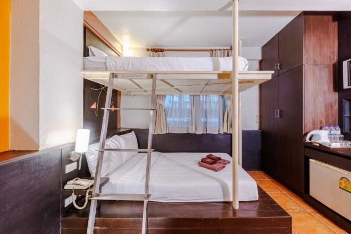 A bunk bed room with a desk, a chair, a lamp, and a cabinet.