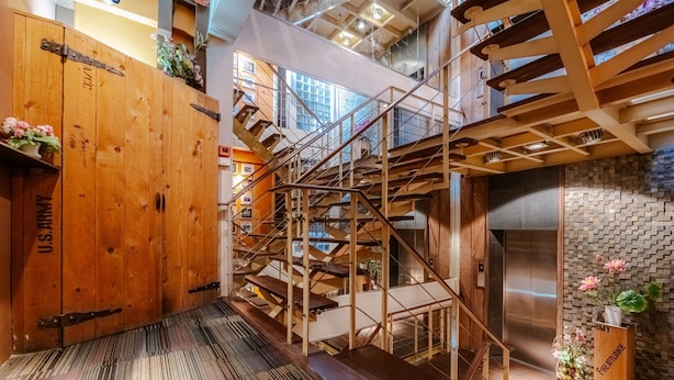 Un intérieur en bois à plusieurs niveaux, avec un escalier, un panneau de l’armée américaine et un mur en briques.