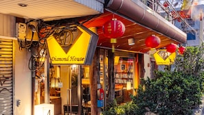 Une librairie nommée « Diamond House », avec une devanture bien visible, une enseigne portant le numéro « 4 » et un petit espace extérieur aménagé avec des plantes, où l’on peut s’asseoir.