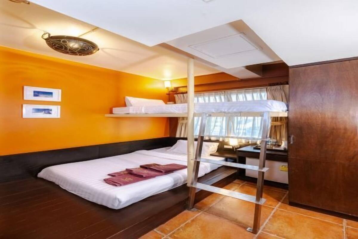 A room with a bunk bed, a desk, a chair, and a wardrobe.