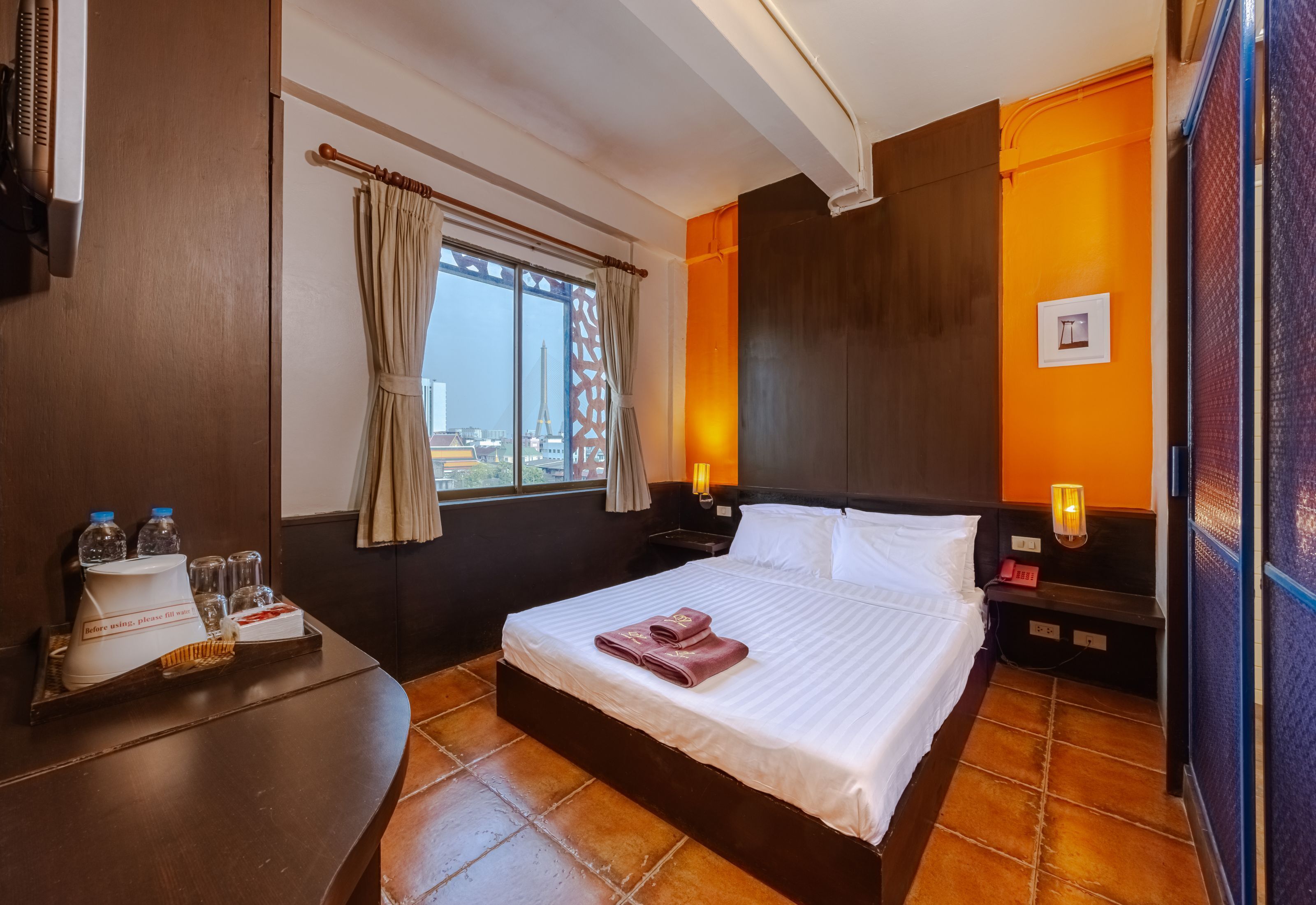 A hotel room with a bed, a nightstand, a window with curtains, a view of the Eiffel Tower, and a tray with breakfast items.