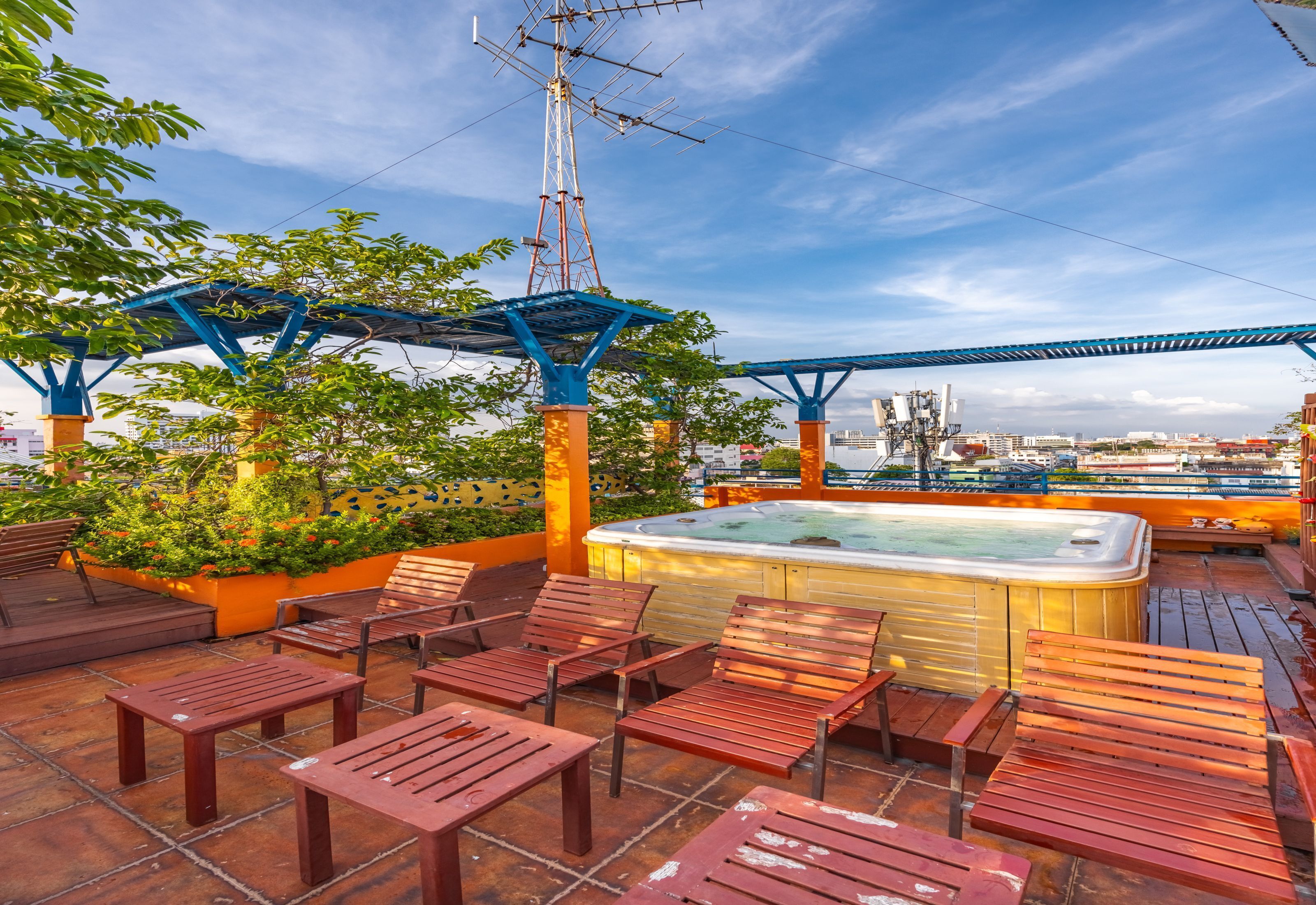 A rooftop terrace with wooden furniture, a hot tub, and a view of the city skyline.