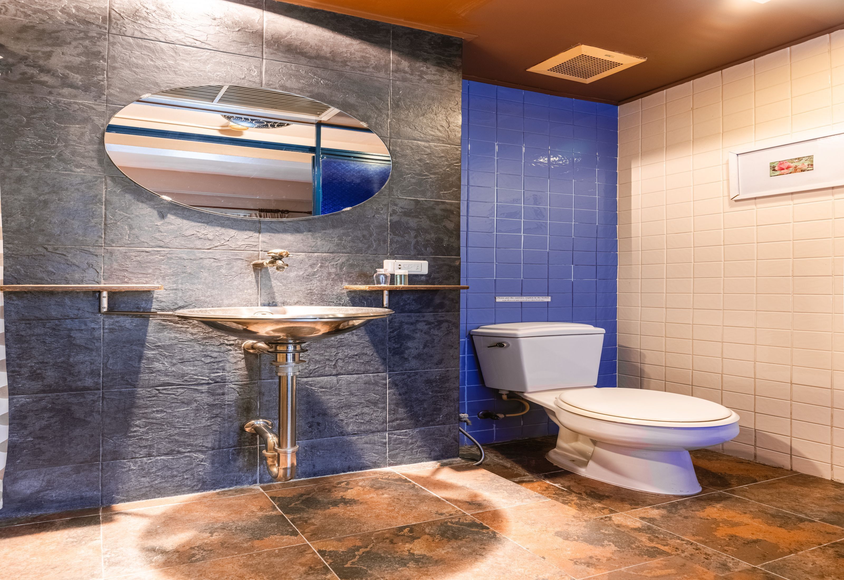 A bathroom with a stone sink, a toilet, and a mirror.