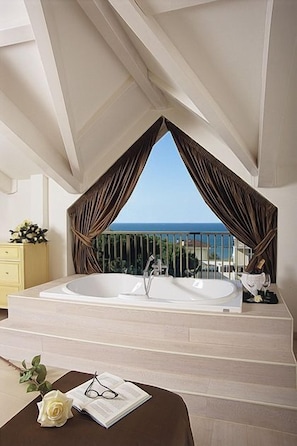 A modern bathroom with a large bathtub, a vanity, and a view of the sea. - M Glamour Hotel (Gabicce Mare)