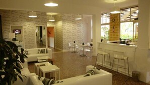 A modern hotel lobby with white furniture, a reception desk, and a patterned wall. - Hotel Amici (Agrigento)