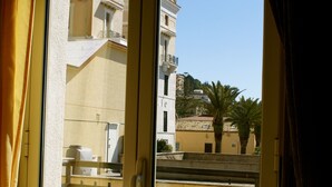 A view from a balcony with a clear sky, a building with a balcony, and a palm tree. - Hotel Amici (Agrigento)