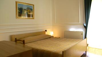 Une chambre d’hôtel avec un lit simple, une table de chevet, une lampe et un radiateur.