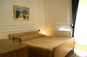 A hotel room with a single bed, a bedside table, a lamp, and a radiator. - Hotel Amici (Agrigento)