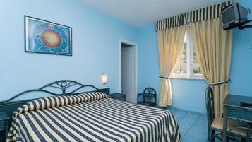 A bedroom with a bed, a desk, a chair, a television, and a door.