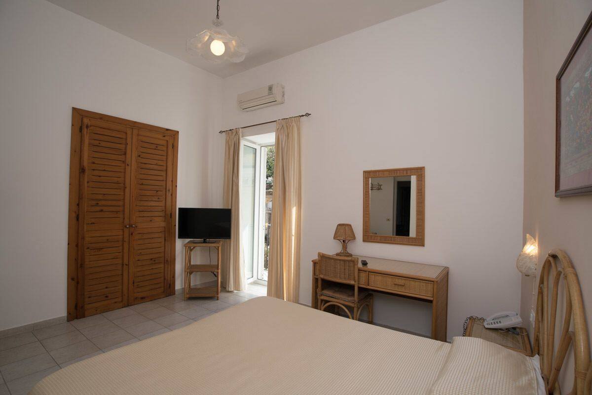 Una camera da letto con un letto, una scrivania, una sedia, una televisione e un armadio.