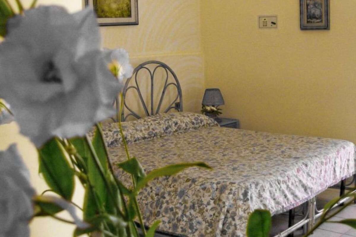 Una camera da letto con un letto, un comodino, una lampada e due quadri appesi al muro.