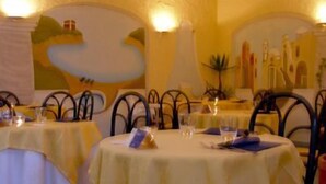 A restaurant with round tables covered in yellow tablecloths, metal chairs, and candles. - Hotel Il Nespolo (Casamicciola Terme)