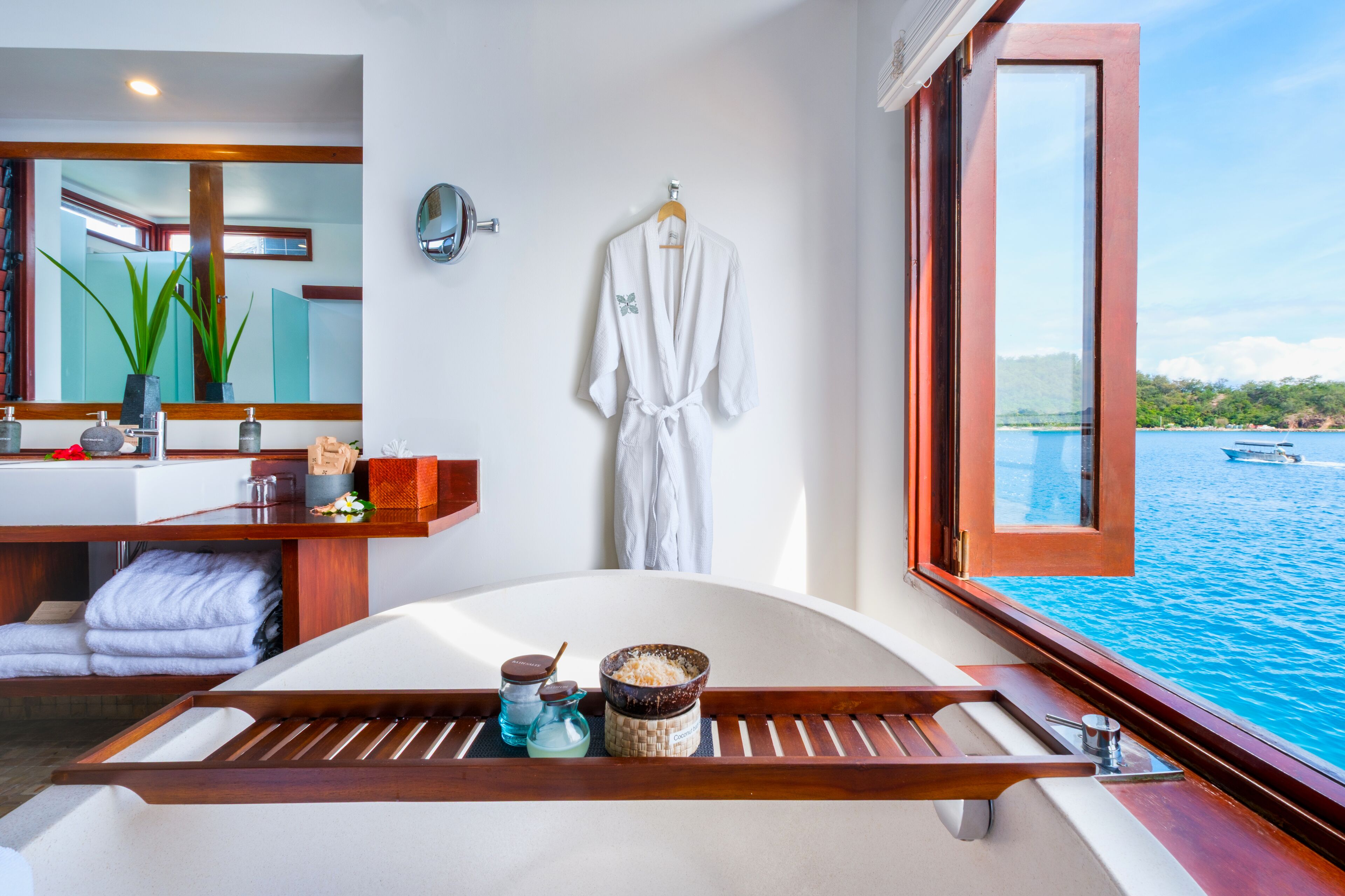 Une salle de bain moderne avec une baignoire, un porte-serviettes et une grande fenêtre donnant sur un plan d’eau.
