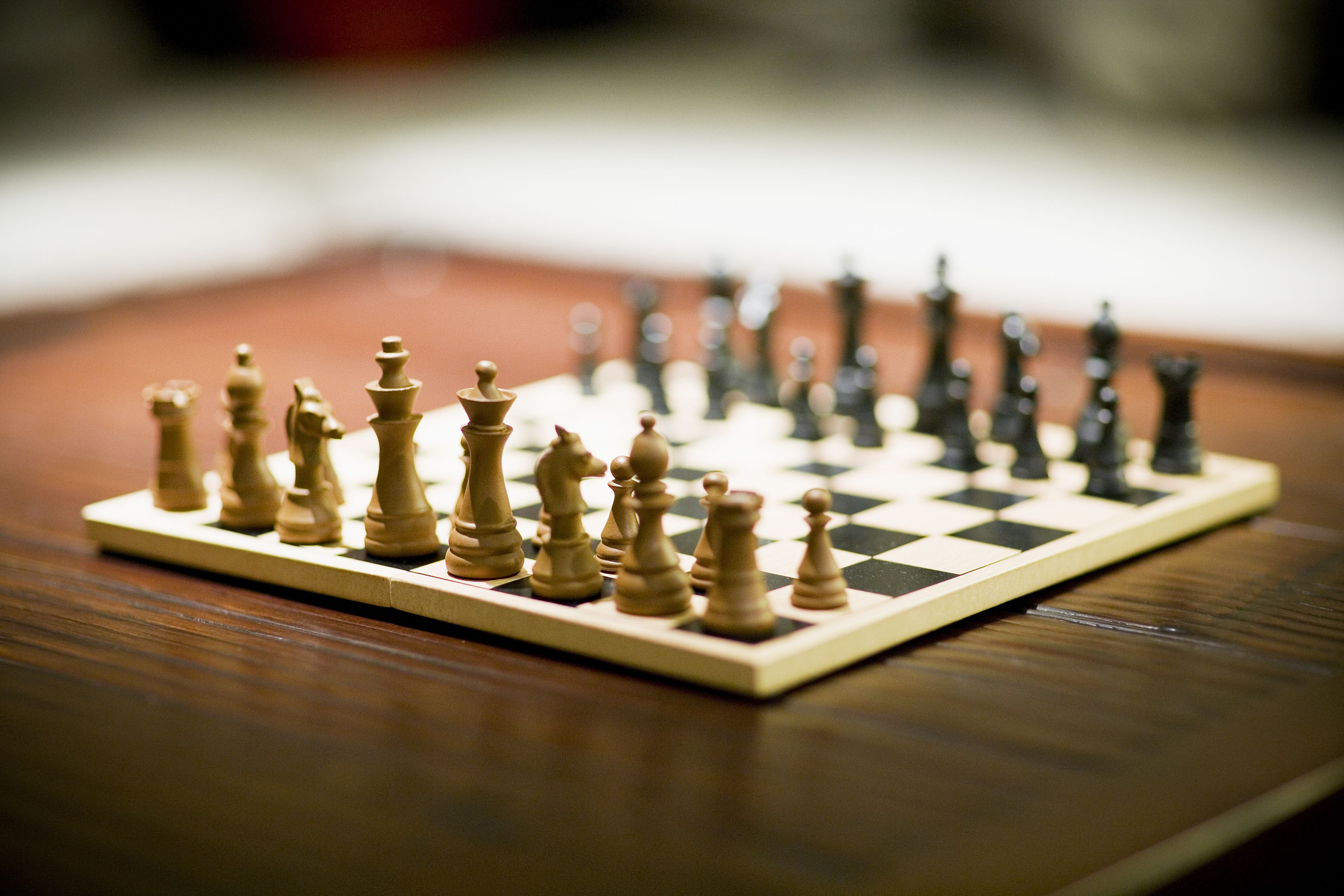A chessboard with pieces on a wooden surface.