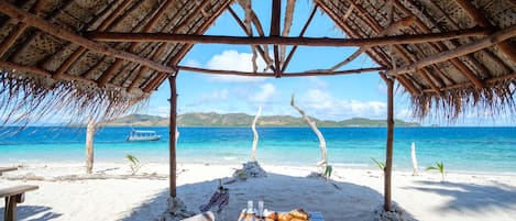 Een privéstrand, wit zand, ligstoelen aan het strand, parasols