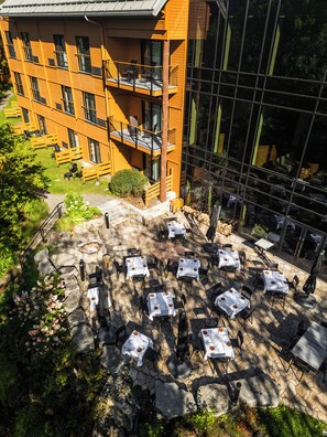 A hotel with outdoor seating and a view of the surrounding greenery. - Hôtel-Musée Premières Nations (Wendake)