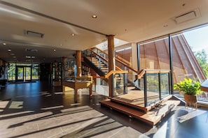 A spacious interior with a wooden staircase, large windows, and a modern design. - Hôtel-Musée Premières Nations (Wendake)