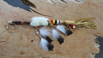 Une surface en bois ornée d’un objet décoratif composé de plumes, de perles et d’un autre objet également orné de plumes.