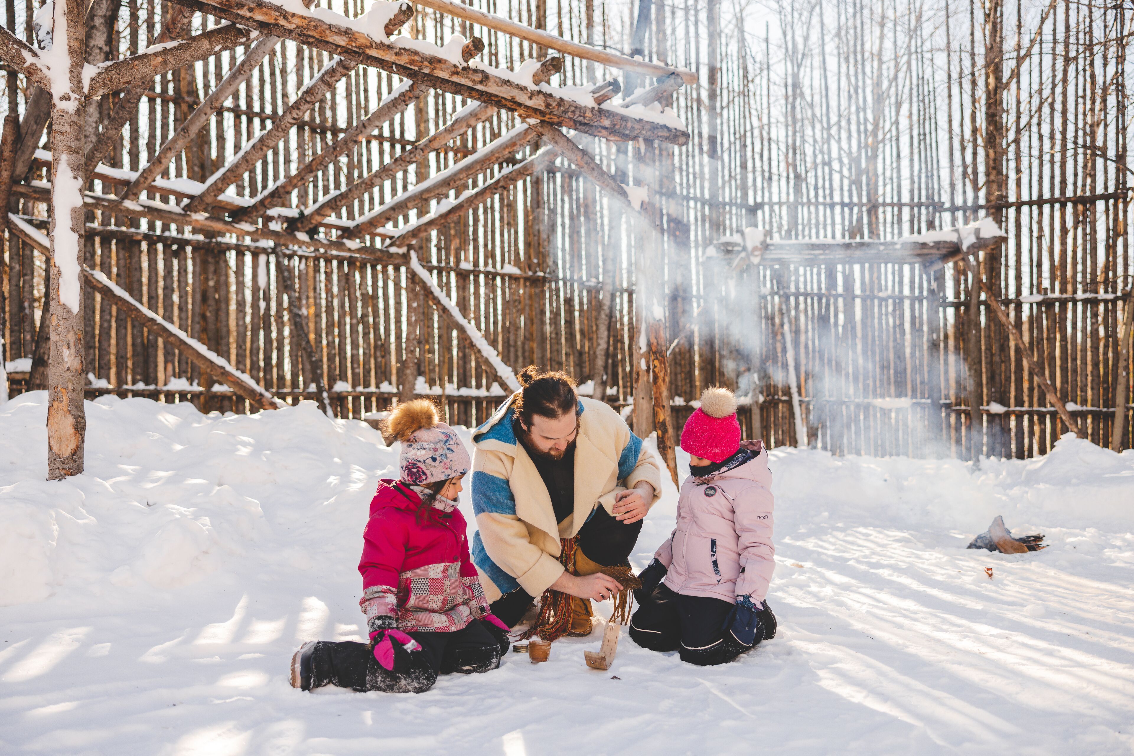 Una familia en un entorno nevado con una estructura de madera al fondo.