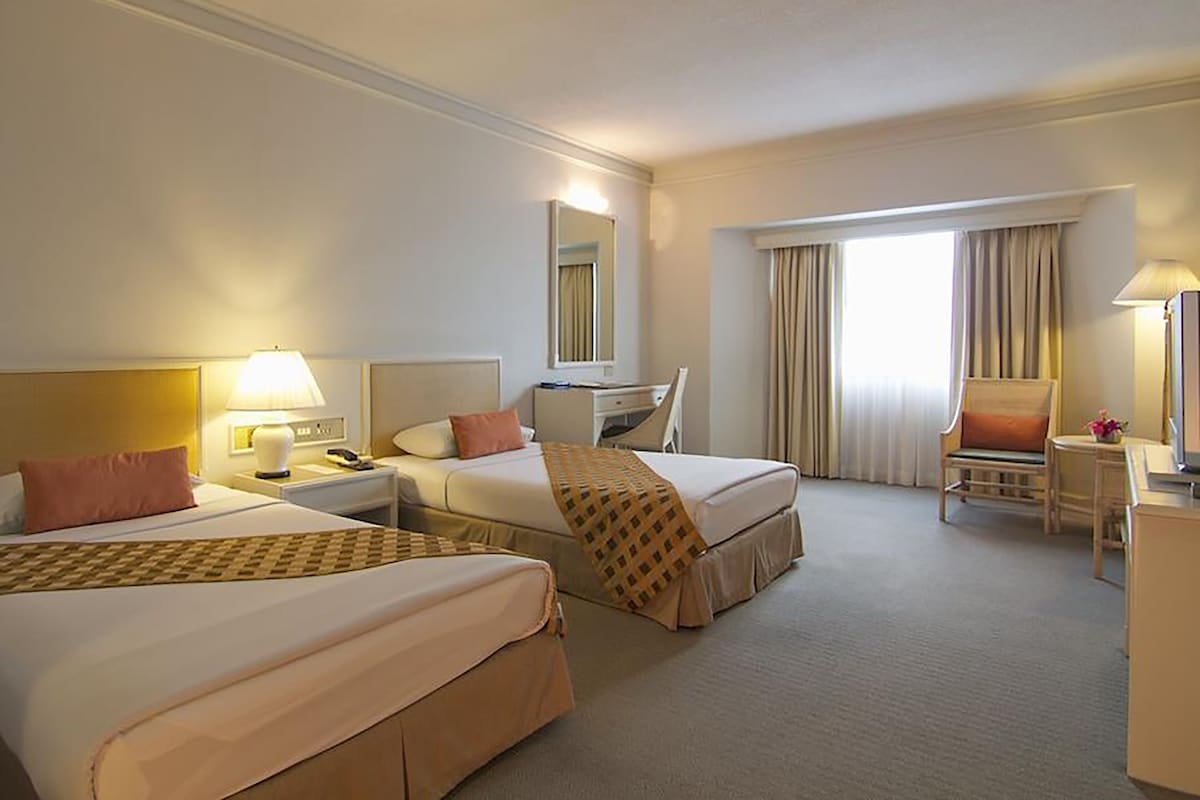 Een hotelkamer met twee bedden, een bureau, een stoel en een televisietoestel.