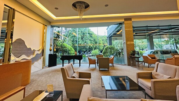 Uma área de estar moderna com sofás, um piano e uma mesa de centro de vidro.