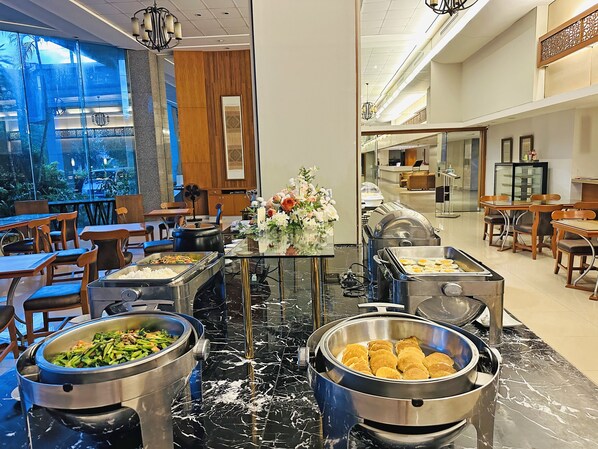 A buffet setup with various food items, a floral centerpiece, and a modern interior design.