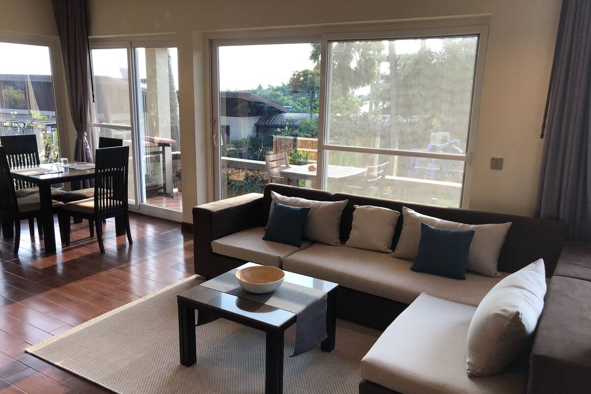 A modern living room with a sofa, a coffee table, and a dining area with chairs and a table.