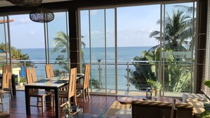 A dining area with a view of the ocean, featuring wooden chairs, a glass table, and a decorative vase. - Royal Beach Boutique Resort & Spa (Koh Samui)