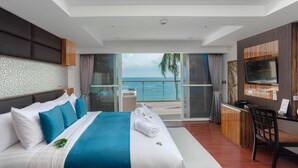 A modern hotel room with a large bed, a desk, a TV, and a balcony with a view of the sea. - Royal Beach Boutique Resort & Spa (Koh Samui)